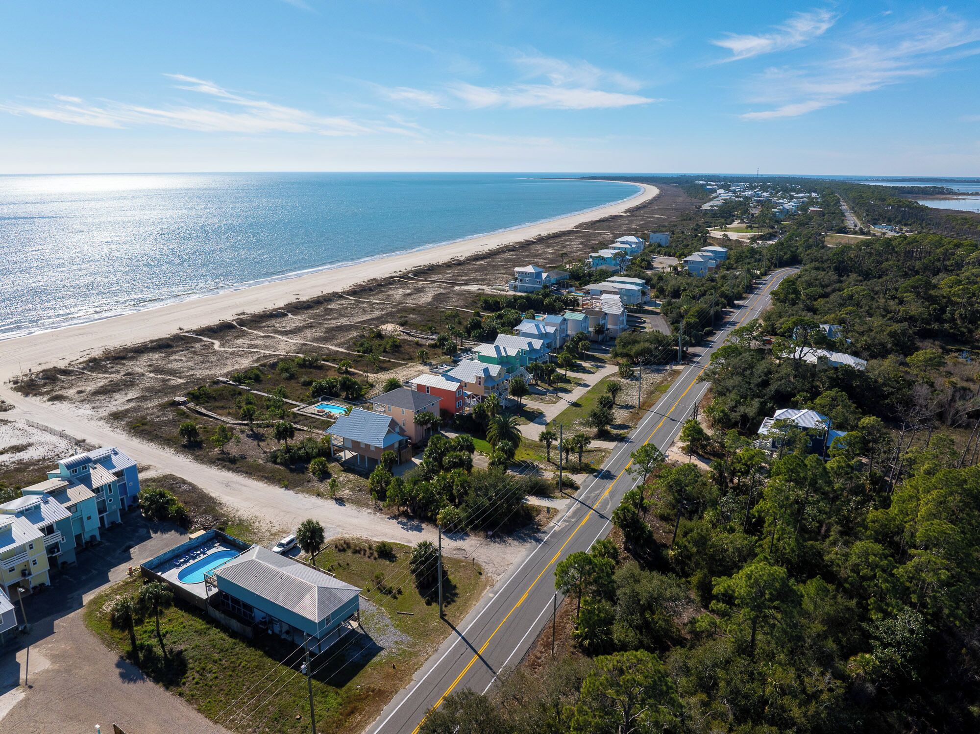 Oversigtsbillede af et kystnære boligområde med huse, en strand og en vej.