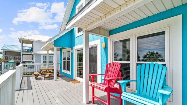 Une terrasse couverte, aménagée avec des meubles en bois et des fauteuils Adirondack.