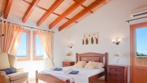 Een slaapkamer met een houten bed, twee nachtkastjes, een stoel en een raam met gordijnen.