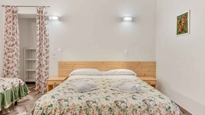 Une chambre avec deux lits, une tête de lit en bois, une table de chevet et un luminaire fixé au mur.