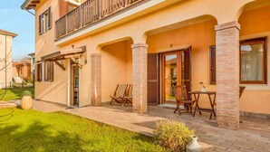Un bâtiment à deux étages doté d’un balcon, d’une terrasse avec des meubles d’extérieur et d’une pelouse bien entretenue.