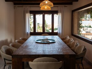 Un comedor con una mesa de madera, seis sillas y una lámpara colgante.