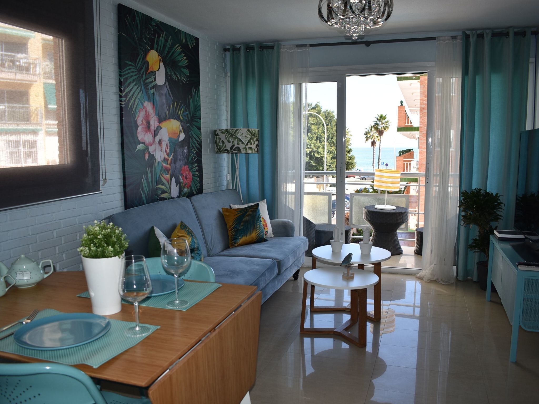 Een moderne woonkamer met een bank, een eettafel en een balkon met uitzicht op zee.