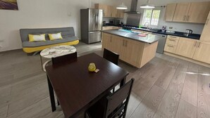 A modern kitchen with a central island, wooden cabinets, and a built-in oven. - Blue Sail Apartments - 1 bedroom apartments (sint maarten)