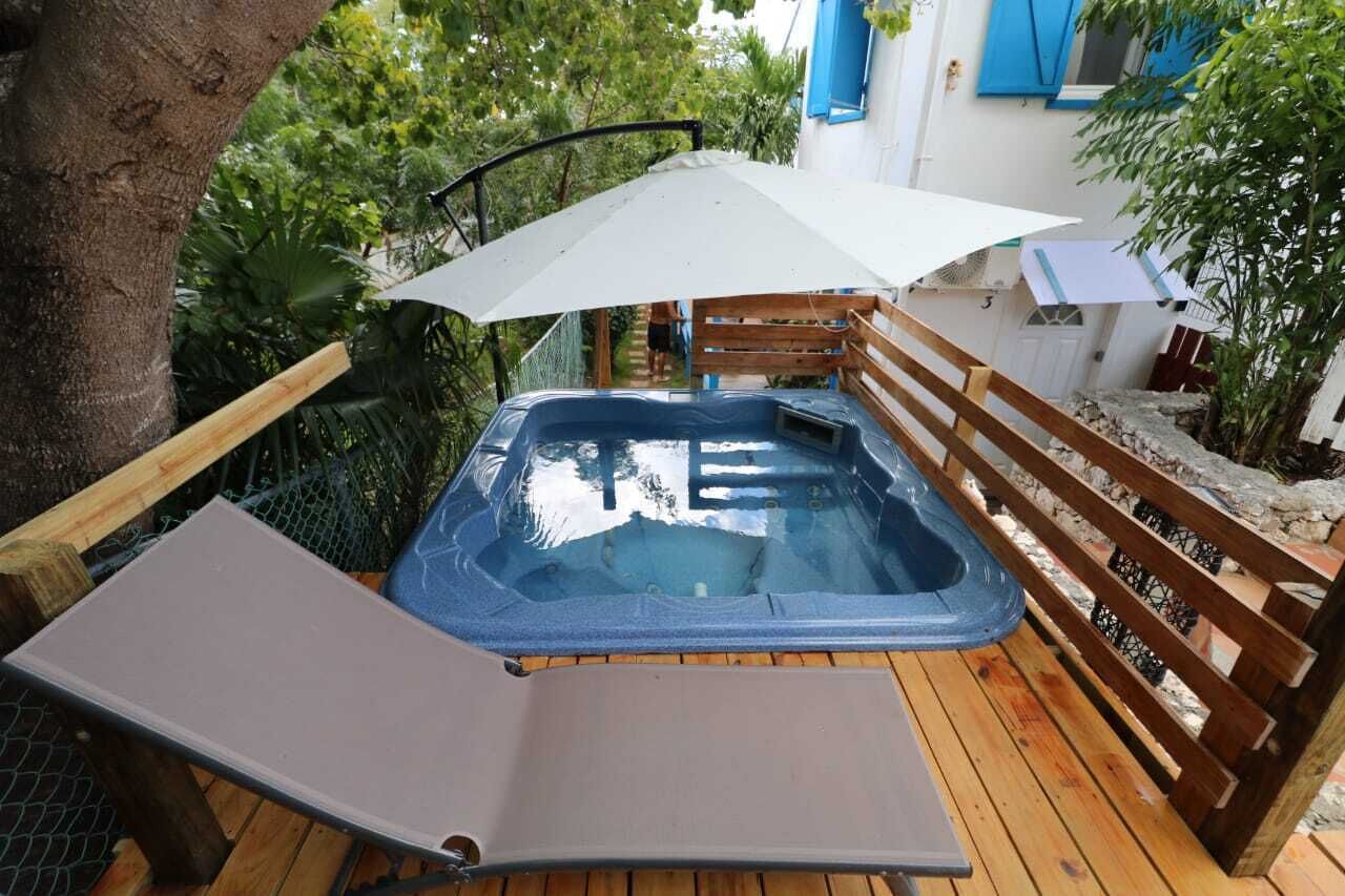 Un bain à remous sur une terrasse en bois, avec une clôture en bois et un arbre à proximité.