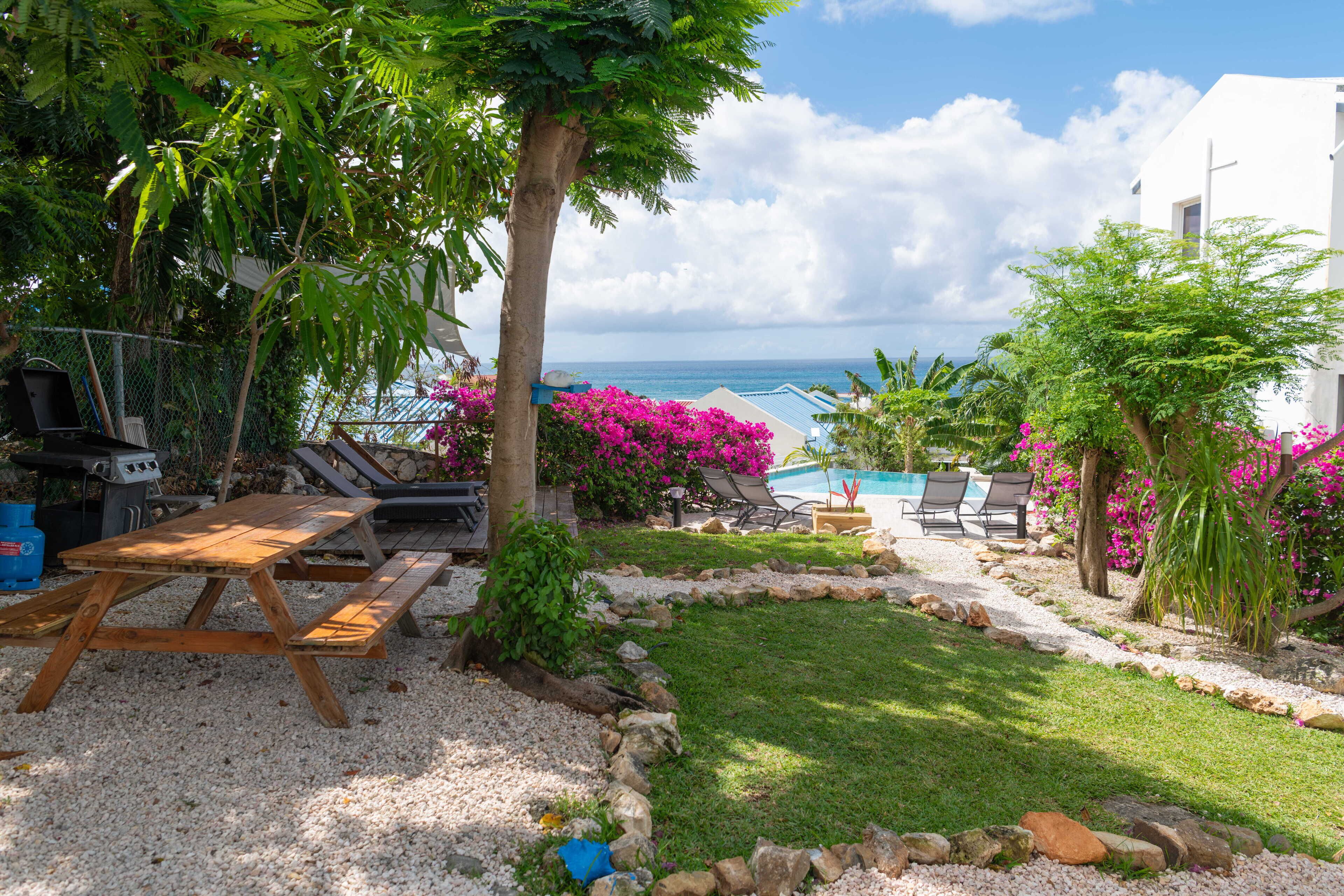A patio with a grill, lounge chairs, and a view of the ocean.