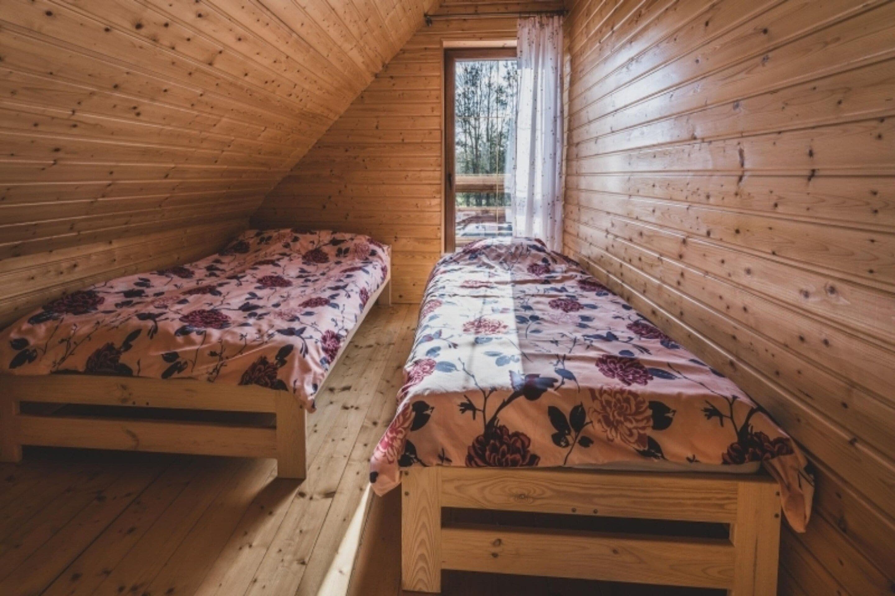 A small, wooden cabin with two single beds, each with floral bedding.