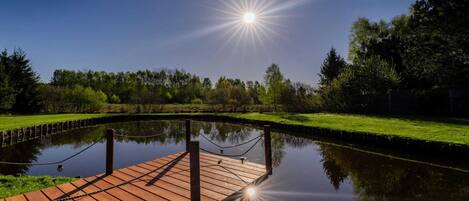 A wooden dock extending over a calm body of water, surrounded by lush greenery and trees.