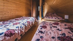 Une cabine avec deux lits simples, des murs en bois et un plafond en pente.