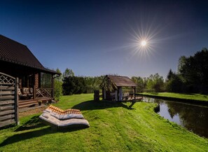 Eine Holzhütte mit Veranda und kleinem Gazebo an einem Teich.