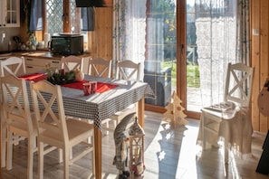 A dining area with a checkered tablecloth, white chairs, a small Christmas tree, and a lantern on the floor. - Holiday Home With Private Pond, Jacuzzi and Sauna (Lipusz)