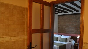 Ein Schlafzimmer mit Holztür, Backsteinwand, Bett mit Kissen und Nachttisch.