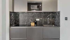 Una cucina moderna con una parete di fondo in marmo nero, un forno a microonde Bosch e un lavello incassato.