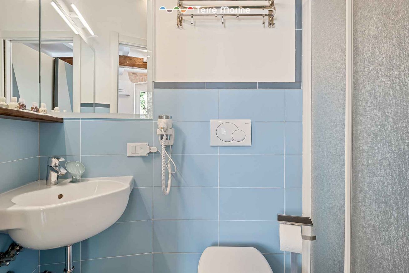 A bathroom with a white sink, a toilet, and a shower. There is a mirror above the sink and a towel rack above the shower.