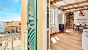 Un balcone con vista sul mare e una zona pranzo con parete in pietra e soffitto in legno.