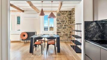 A modern kitchen with a black marble countertop, a dining area with a table and chairs, and a stone wall.