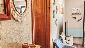 Una stanza con una porta in legno, uno specchio, uno scaffale con contenitori di legno, una sedia e decorazioni a parete.