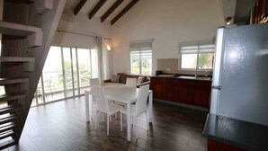 Una cocina amplia con comedor, piso de madera y un ventanal que proporciona luz natural.