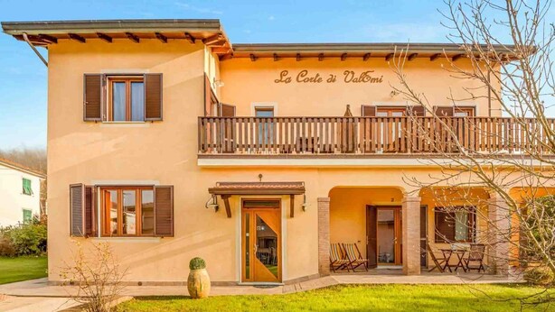 Ein zweistöckiges Gebäude mit Balkon, einem Schild mit der Aufschrift 'La Corte di Valtori' und Außenbestuhlung.