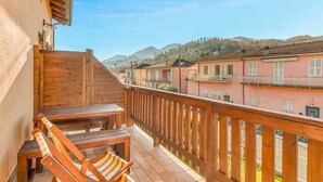Ein Balkon mit Holzmöbeln, Blick auf benachbarte Gebäude und einen klaren Himmel.