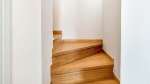 Una stretta scala in legno in un corridoio dalle pareti bianche.