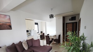 Uma sala de estar moderna com um sofá modular, uma mesa de centro e uma área de jantar com cadeiras.