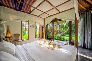 Una camera da letto con un grande letto, una baldacchino e vista su un giardino rigoglioso.