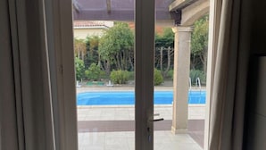 An outdoor area with a swimming pool, surrounded by greenery and a covered patio area. - Detached Family Villa in Les Cammazes (Les Cammazes)