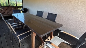 A wooden deck with a long table and chairs, a sign reading "THIS IS OUR HAPPY PLACE", and a lantern on the wall. - Detached Family Villa in Les Cammazes (Les Cammazes)