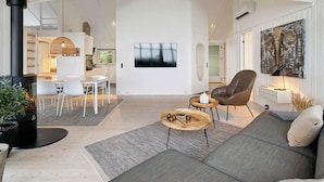 Una sala de estar moderna con chimenea, comedor y cocina.