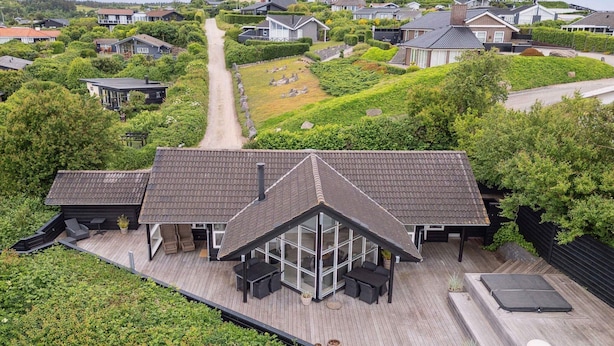 Una casa moderna con una amplia terraza, varias habitaciones y vistas panorámicas de una zona residencial.