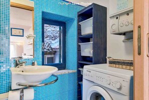 Une salle de bain avec un lavabo, un miroir et un lave-linge.