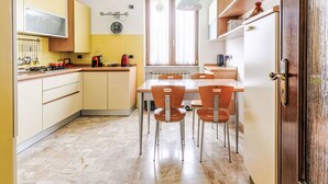Una cucina compatta con zona pranzo, completa di fornello, bollitore e orologio a parete.