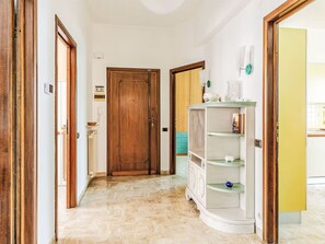 Ein Korridor mit Holztüren, einem weißen Schrank mit Regalen und einem gefliesten Boden.