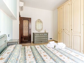 Ein Schlafzimmer mit Bett, Kommode, Kleiderschrank und Spiegel.