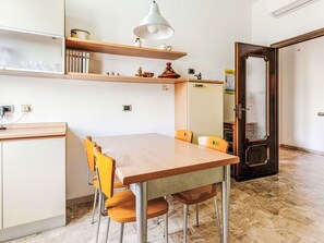 Eine moderne Küche mit einem Holztisch, gelben Stühlen und einer hängenden Leuchte.