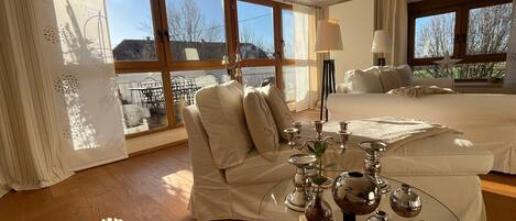 Habitación de hotel con una cama grande, un área de descanso con una mesita de vidrio y vistas al exterior.