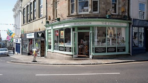 A corner shop named 'The Cornish Hen' with a green facade and a display window. - cozy one-bed apartment in the heart of Penzance (Penzance)