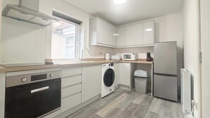 A compact kitchen with a dishwasher, washing machine, microwave, and refrigerator. - cozy one-bed apartment in the heart of Penzance (Penzance)