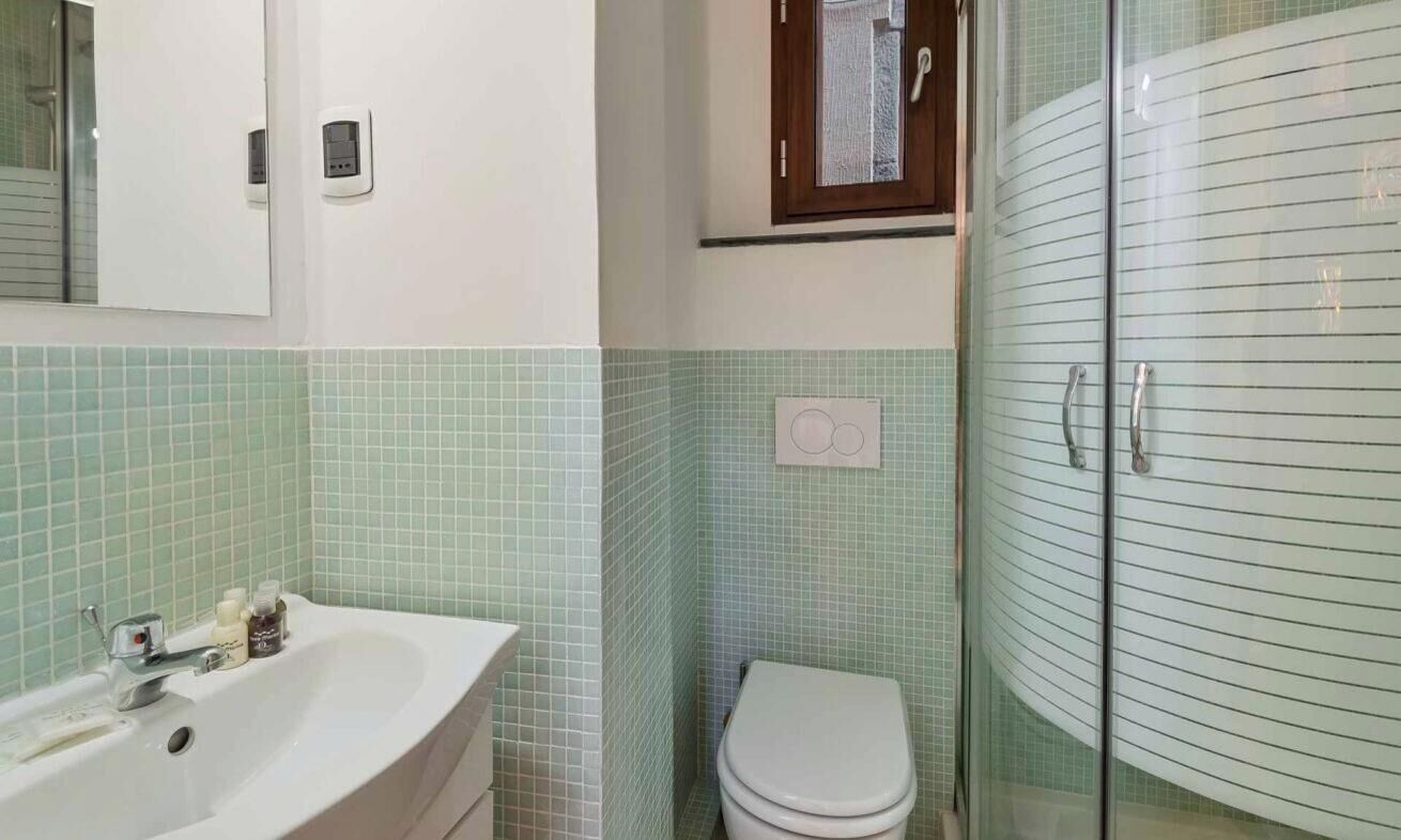 Een badkamer met een wastafel, toilet en douchecabine van glas.