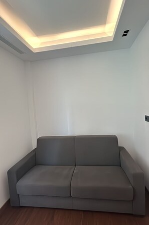 A modern room with a grey sofa, white walls, and recessed ceiling lighting. - Strand Canteras III by Interhome (Las Palmas)