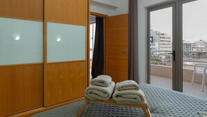 Ein Hotelzimmer mit einem großen Bett, einem Holzschrank mit Milchglasfronten und einem Balkon mit Blick auf die Stadt.