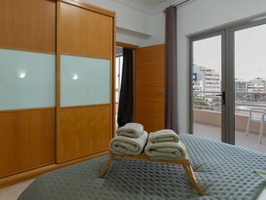 A hotel room with a large bed, a wooden wardrobe with frosted glass panels, and a balcony with a city view. - Appartement mit Blick auf das Meer by Interhome (Las Palmas)