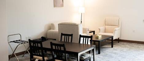 Un área de comedor con una mesa, sillas, un sofá y una lámpara.