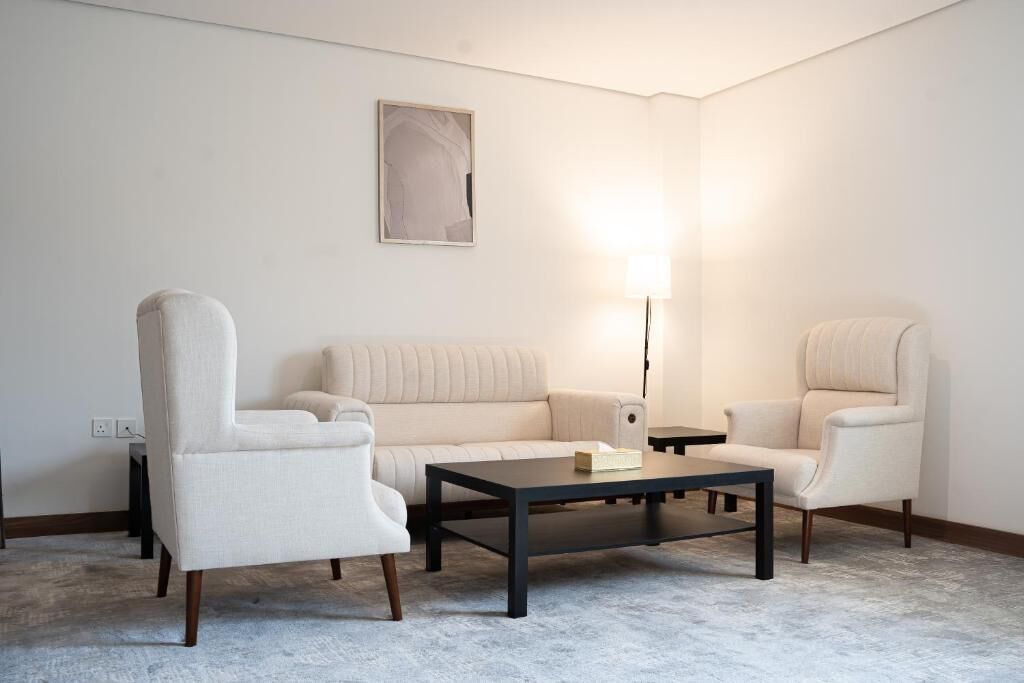 Una sala de estar moderna con un sofá color crema, dos sillones, una mesita de centro y una lámpara de pie.