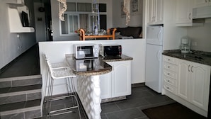 A modern kitchen with white cabinetry, a granite countertop, a built-in microwave, and a coffee maker.