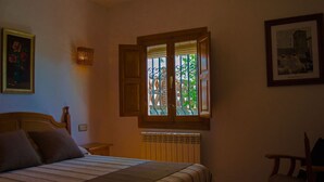 Una camera da letto con un letto, una finestra vista verde, un termosifone e una sedia.