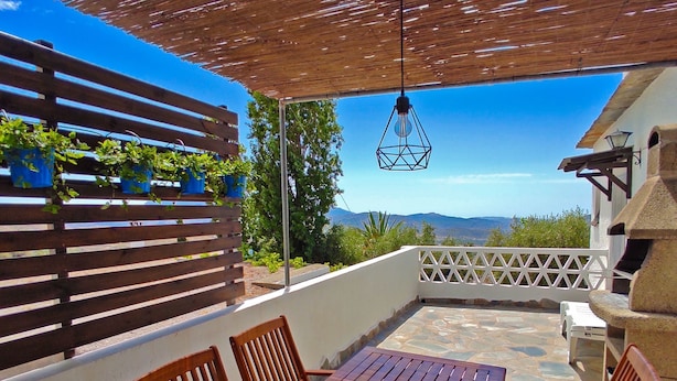 Un tavolo e delle sedie in legno sotto una pergola con vista sulle montagne.