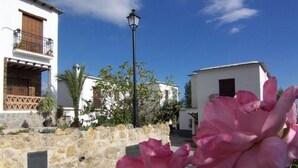 Una strada con muri in pietra, un edificio bianco con un balcone e un lampione.