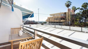A balcony with a table and chairs, overlooking a cityscape with buildings and palm trees. - Home2Book Stylish Studio by the Sea Los Cristianos (Los Cristianos)